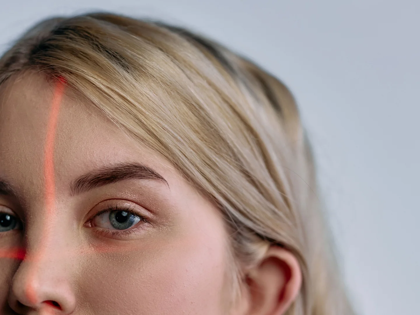 Illustrative portrait crossed by red facial scanning lines, representing synthetic identity and clinician deepfake risk