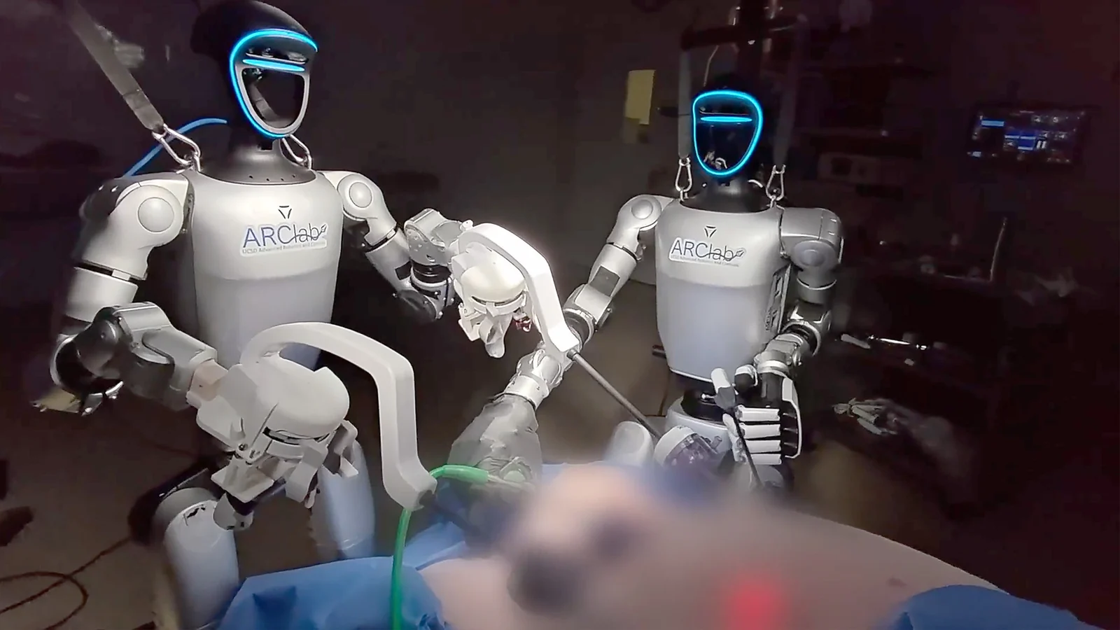 Two teleoperated humanoid robots positioned beside an operating table during a preclinical surgical procedure.