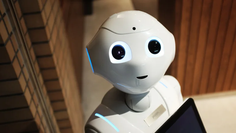 White humanoid robot looking toward the camera while holding a tablet