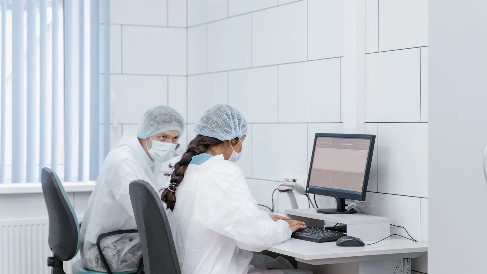 Two laboratory researchers reviewing information on a desktop computer