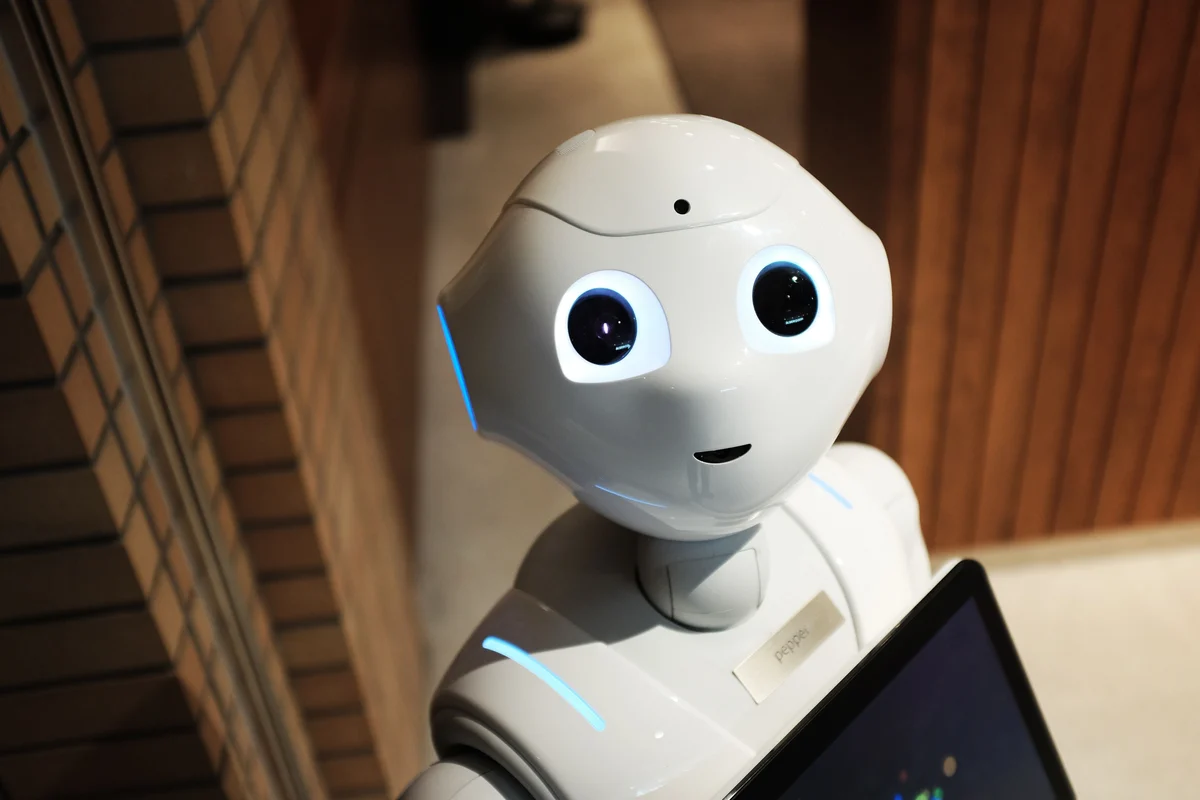 White humanoid robot looking toward the camera while holding a tablet