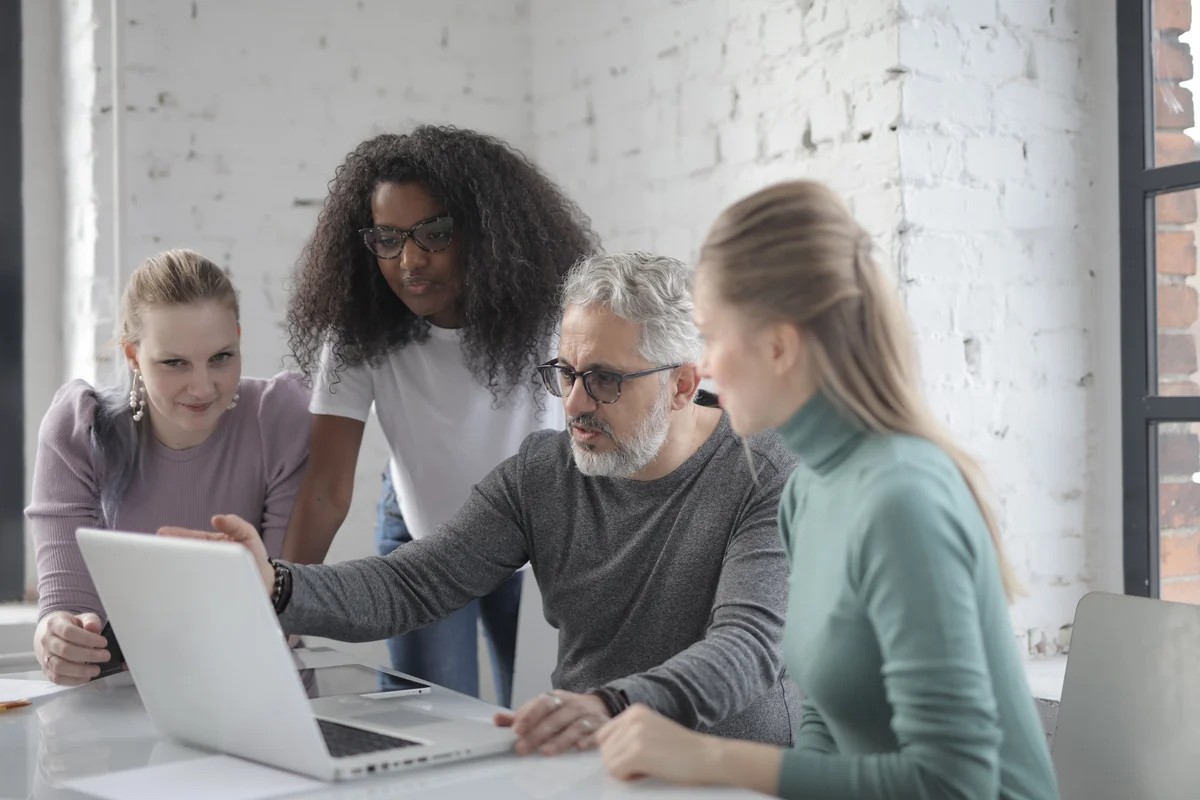 Four colleagues gathered around a laptop in a collaborative working session