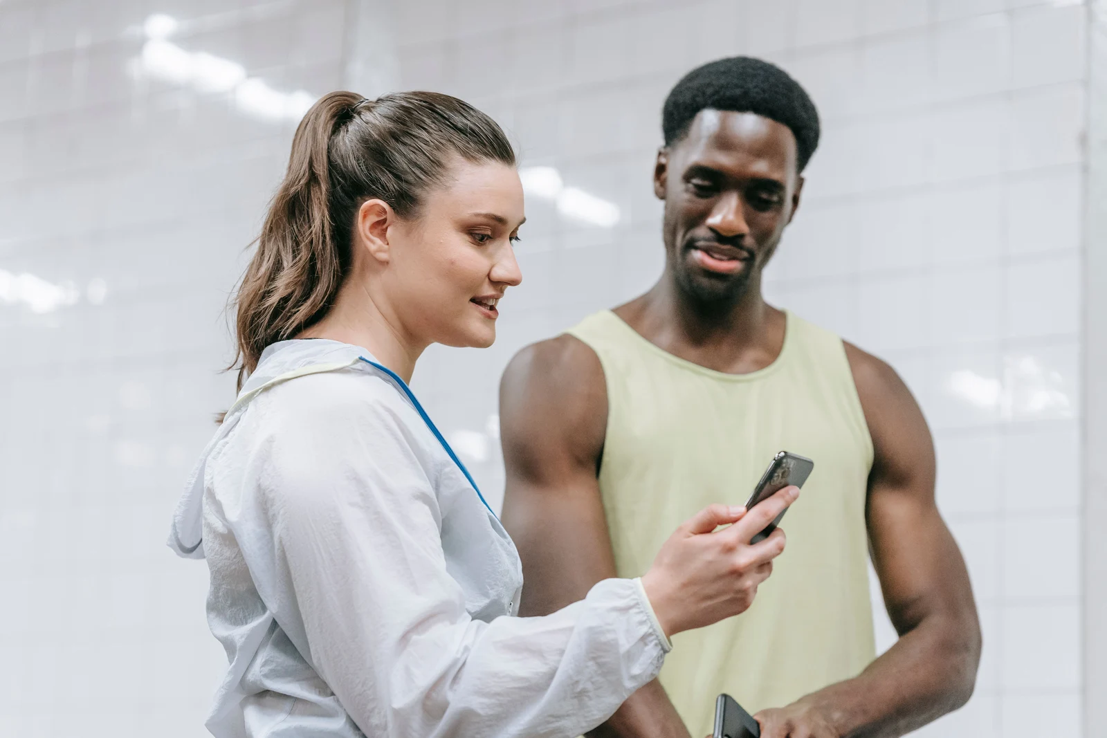 Two people looking together at a smartphone in a bright indoor space.
