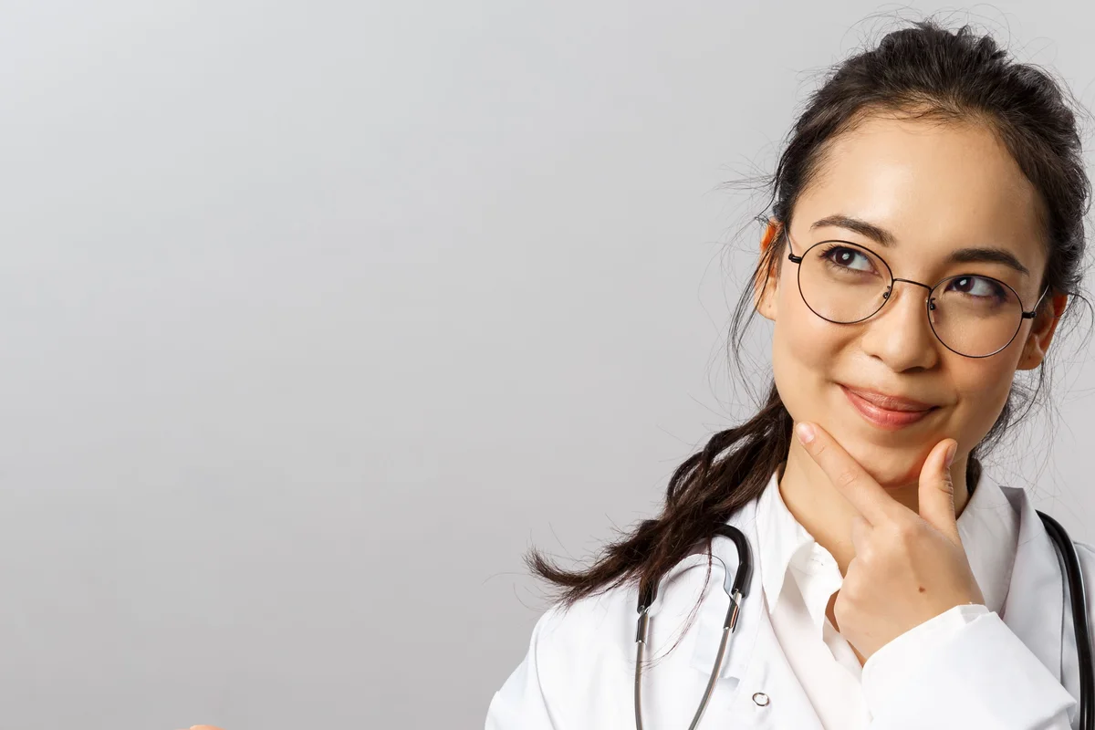 Clinician in a white coat and glasses looking thoughtful, representing clinical medical AI in professional workflows.